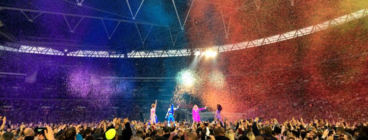 Geri, Melanie C, Emma und Mel B sind von hinten im Wembley Stadion zu sehen. Die Spice Girls stehen in einem Regen aus Regenbogenkonfetti